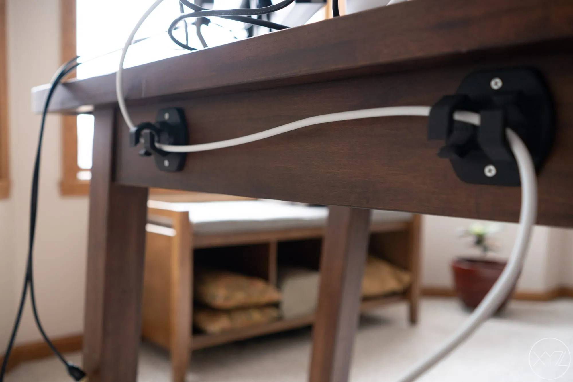 Cable routing clips screwed to the back edge of the desk