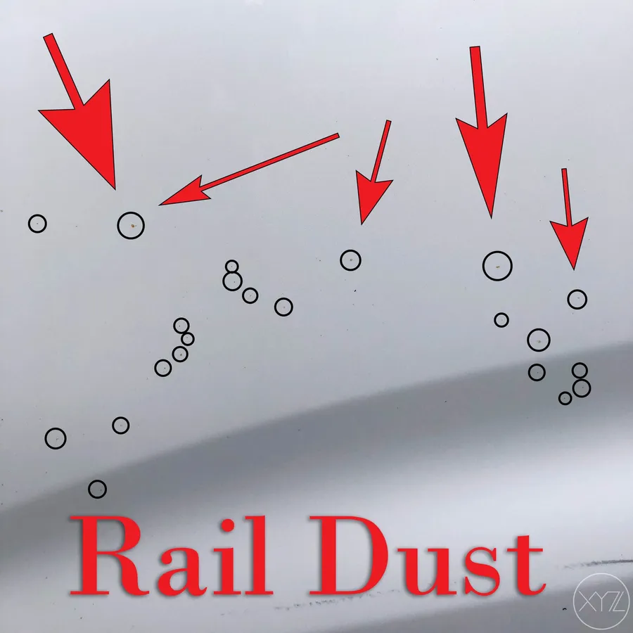 Close-up of yellow rail dust rust spots on white car paint before cleaning